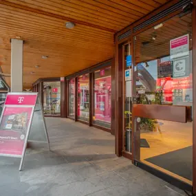 Eingang eines Telekom Shops mit Werbeaufsteller und Beratung für Geschäftskunden.