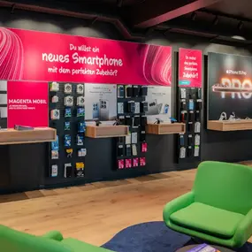 Modernes Telekom-Shop-Interieur mit Smartphone-Zubehör und Werbetafeln für Mobilfunkangebote.