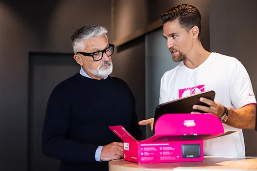 Mitarbeiter berät Kunden mit Tablet zu pinker Produktbox im Shop