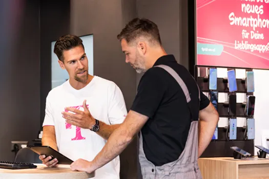 Verkäufer berät Kunden im Handyshop zu Smartphones und Mobilfunkvertrag.