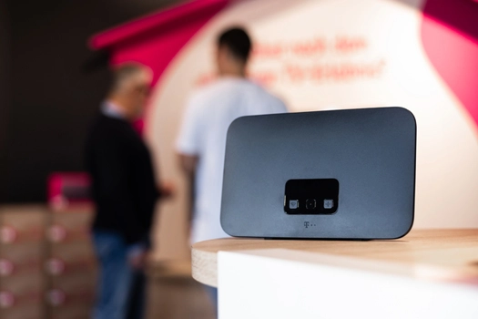 Telekom WLAN-Router auf Tisch im Shop, Kunden im Hintergrund unscharf